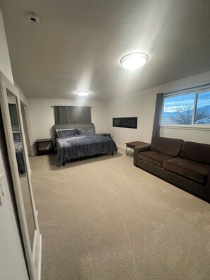 Ein Schlafzimmer mit einem Bett, einer Couch, einem Fernseher und einem Fenster mit Blick.