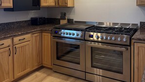 A kitchen with wooden cabinets, a stainless steel range hood, a microwave, and a gas stove.