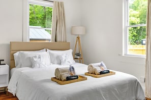 A hotel room with a large bed, a bedside table, a lamp, and a window with curtains. - Boutique Wellness Retreat with Hot Tub Sleeps 5 Pets OK (Greenville)