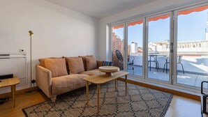 Un salon moderne avec un canapé beige, une table basse en bois et un tapis à motifs.