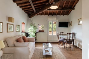 A living room with a sofa, coffee table, and dining area with chairs. - Stunning Rooftop Views in the Heart of Trastevere (Roma)