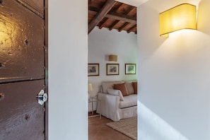 A room with a wooden door, a sofa, a lamp, and framed pictures on the wall. - Stunning Rooftop Views in the Heart of Trastevere (Roma)