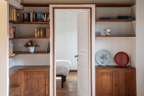 A room with a bed, wooden shelves with books, a white door, and a cabinet with two plates. - Stunning Rooftop Views in the Heart of Trastevere (Roma)