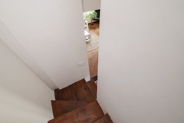 A staircase leading to a room with a white wall and a wooden floor. - Stunning Rooftop Views in the Heart of Trastevere (Roma)