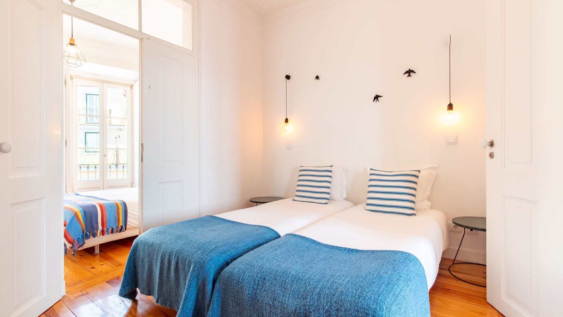 A double room with two beds, a small table, and a bench.