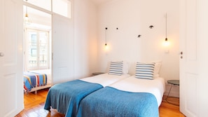 A double room with two beds, a small table, and a bench. - Alfama Balcony River View by LovelyStay (Lisboa)