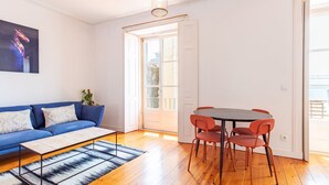 Un salon moderne avec un canapé bleu, une table basse et une table à manger avec des chaises.