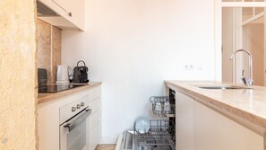 A compact kitchen with a built-in oven, a coffee maker, and a dishwasher. - Alfama Balcony River View by LovelyStay (Lisboa)