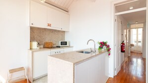 A modern kitchen with white cabinetry, a marble countertop, a microwave, a toaster, and a sink. - Alfama Terrace River View by LovelyStay (Lisboa)