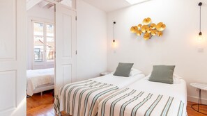A bedroom with a bed, a bedside table, a wall-mounted light fixture, and a window. - Alfama Terrace River View by LovelyStay (Lisboa)