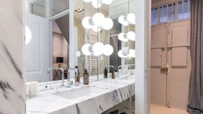 Um banheiro com espelho grande, várias pias e luminárias modernas.