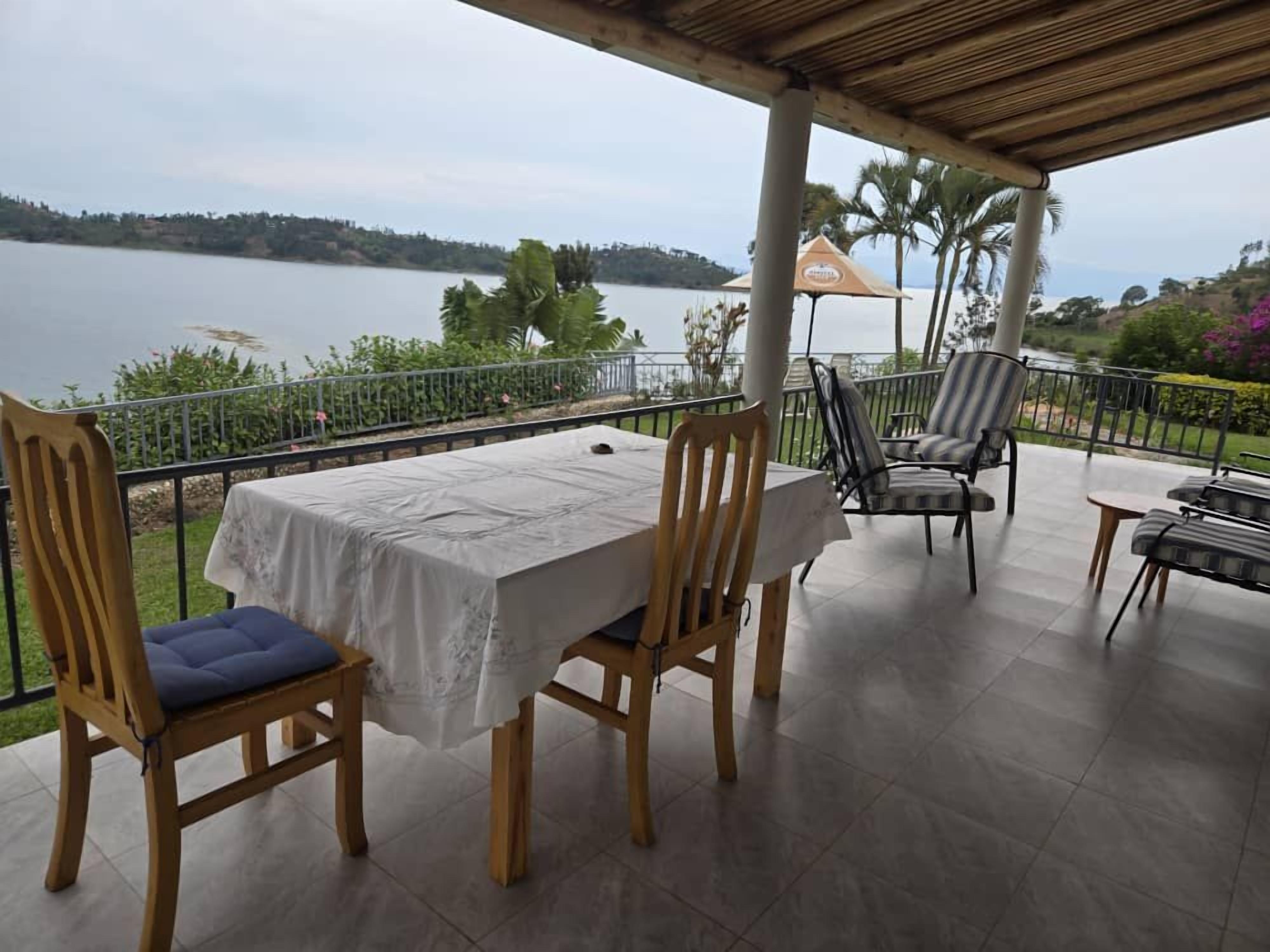 Un espacio de comedor al aire libre techado con mesa y sillas, con vistas a un cuerpo de agua.