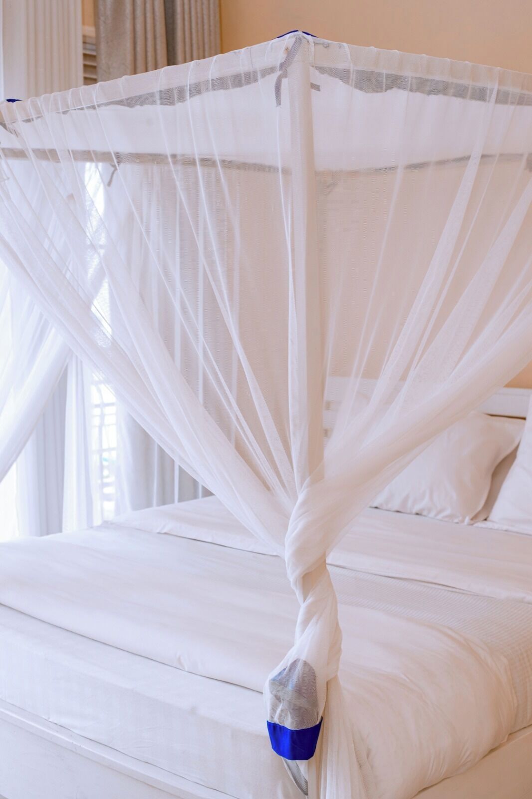 A bed with a white canopy and a blue and gray striped pillow.