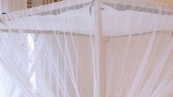 A bed with a white canopy and a blue and gray striped pillow.
