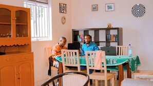 Une pièce comprenant une table à manger, des chaises, un buffet et deux personnes assises à la table.