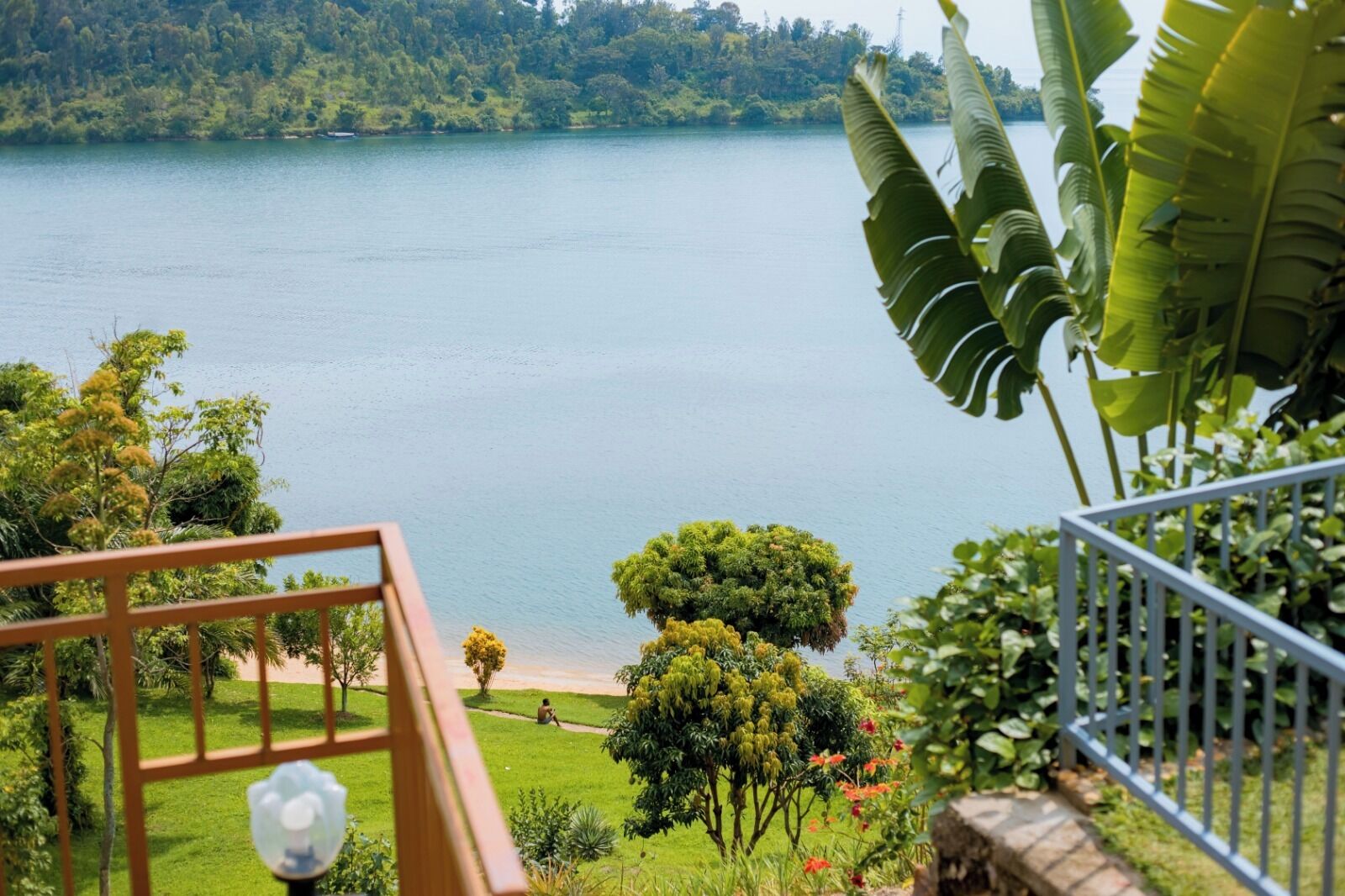 Vista desde un balcón sobre un lago, con abundante vegetación y una orilla lejana.