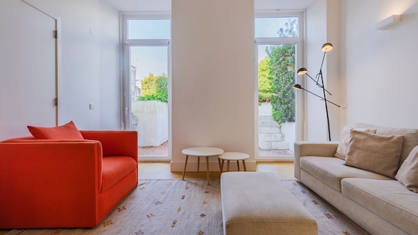 Ein modernes Wohnzimmer mit einem roten Sofa, einem beigen Sofa und einem kleinen runden Tisch.
