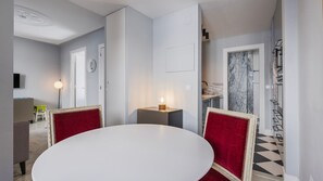 Ein Essbereich mit einem weißen Tisch, roten Polsterstühlen und einer kleinen Tischleuchte.