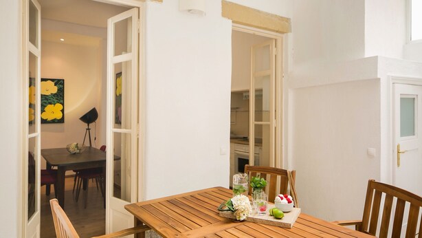 Un tavolo da pranzo in legno con frutta e bevande, una sedia e vista su una zona cucina.