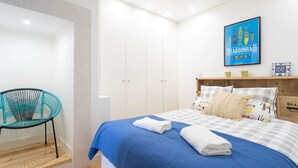 Un dormitorio con cama, una silla y un armario.