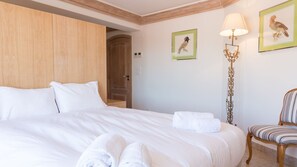 Ett hotellrum med en stor säng, en garderob i trä, en stol och två inramade tavlor på väggen.