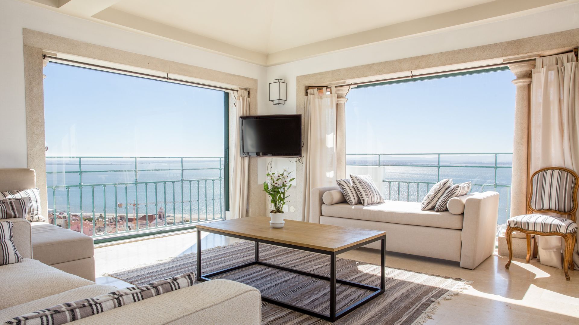 Un salón amplio con balcón, un televisor de pantalla plana y vistas al mar.