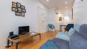 Een moderne woonkamer met een flatscreen televisie, een houten salontafel en een bank.