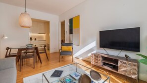 A modern living room with a glass coffee table, a flat-screen TV, and a wooden entertainment unit. - Downtown Sleek Apartment by LovelyStay (Lisboa)