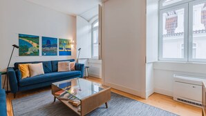 Ett modernt vardagsrum med en blå soffa, ett soffbord i glas och konstverk på väggen.