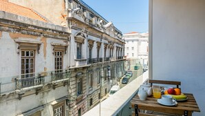 Un balcone con un tavolo apparecchiato per il tè, con vista su una strada con auto ed edifici.