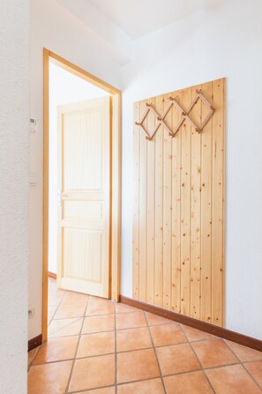 A hallway with a wooden door, a wooden wall-mounted rack, and a tiled floor. - Bright Chalet with mountain view terrace - panoramic first floor (La Salle-les-Alpes)