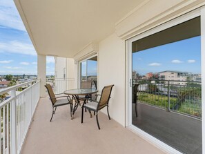 A balcony with a table and chairs, a view of the city, and a clear sky. - Madeira Norte 416 (Madeira Beach)