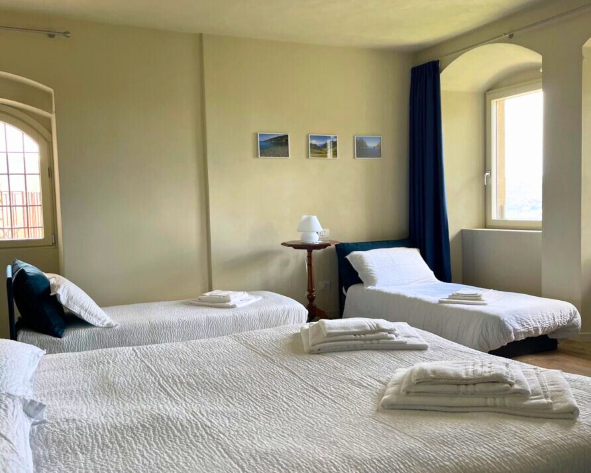 Une chambre d’hôtel avec deux lits, une petite table avec une lampe et une fenêtre avec des rideaux.