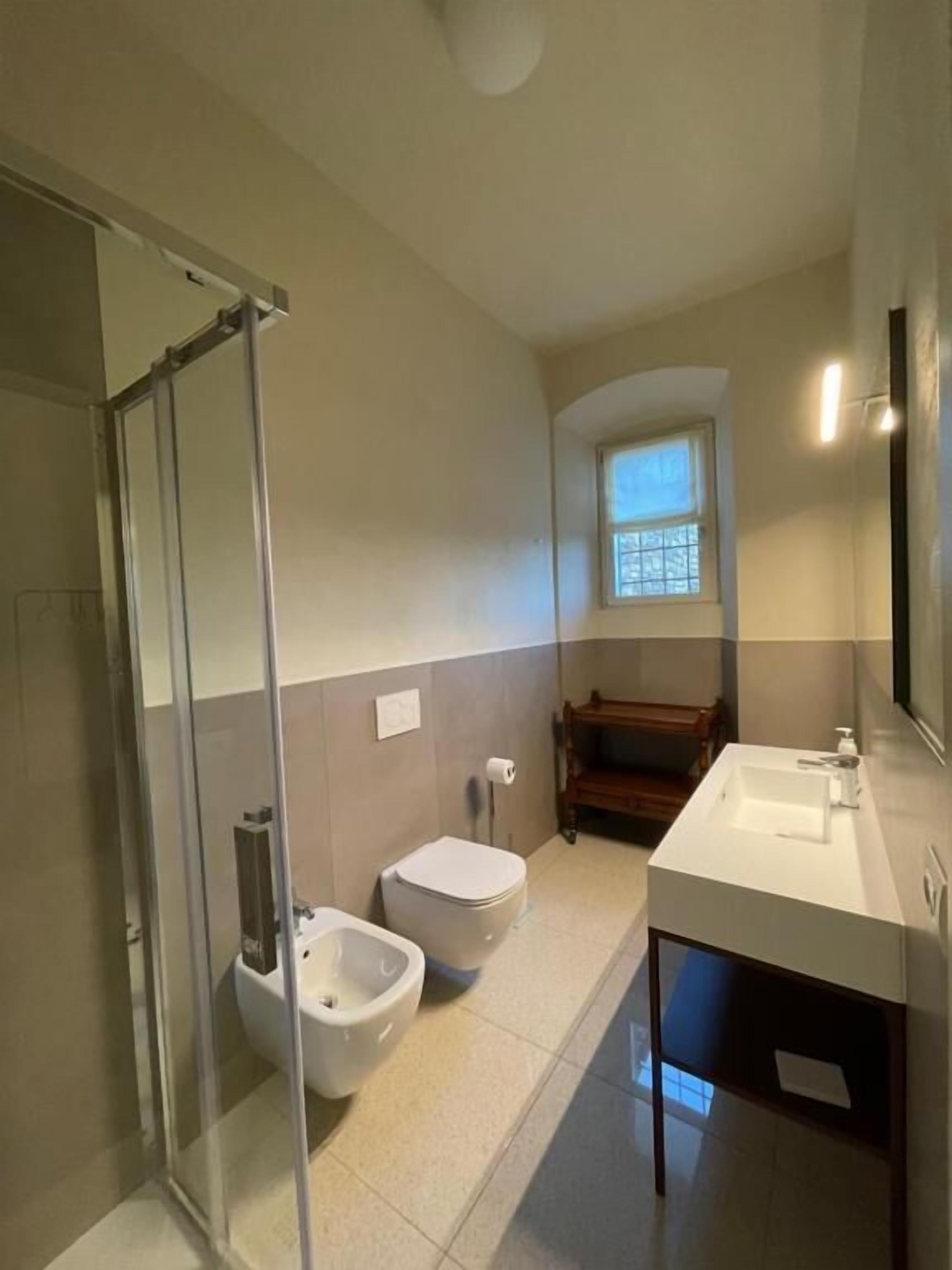 Une salle de bain avec une douche à parois de verre, des toilettes, un bidet et un lavabo.