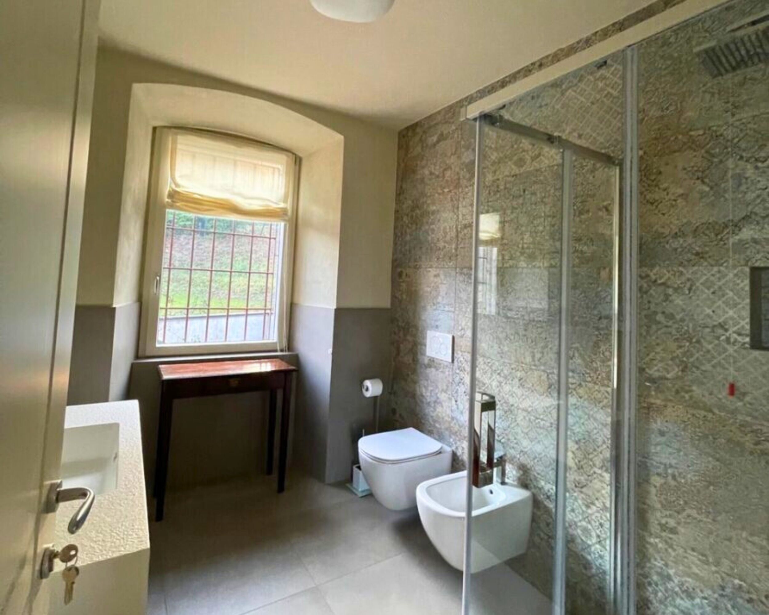 A bathroom with a toilet, bidet, and a glass shower enclosure.