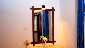 A mirror with a wooden frame mounted on a wall, a small potted plant, and a light fixture above the mirror. - Ella Mountain Breeze Villa: King Suite with Balcony (Ella)