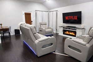 A modern living room with leather sofas, a fireplace, and a TV displaying 'NETFLIX'. - Rally & Rest — Heated Massage Chairs, Pool Table, 4 miles to AT&T Stadium (Grand Prairie)
