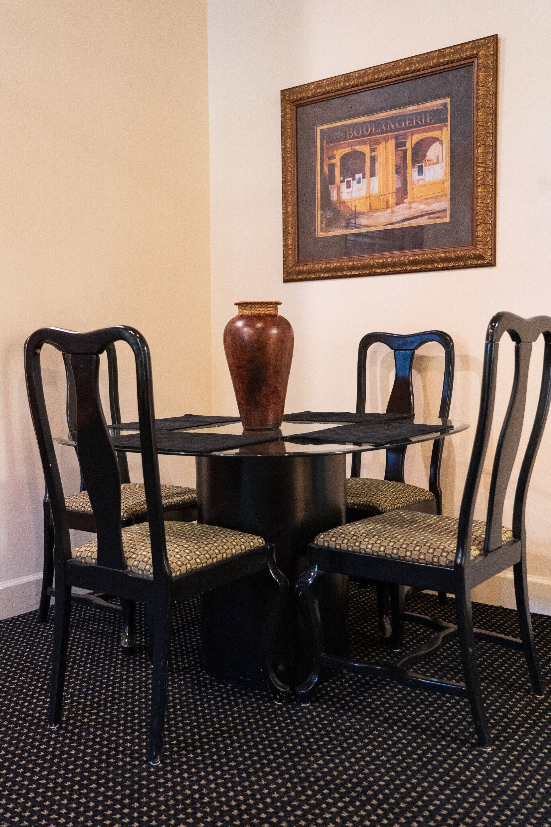 A dining area with a round table, two chairs, and a large vase.