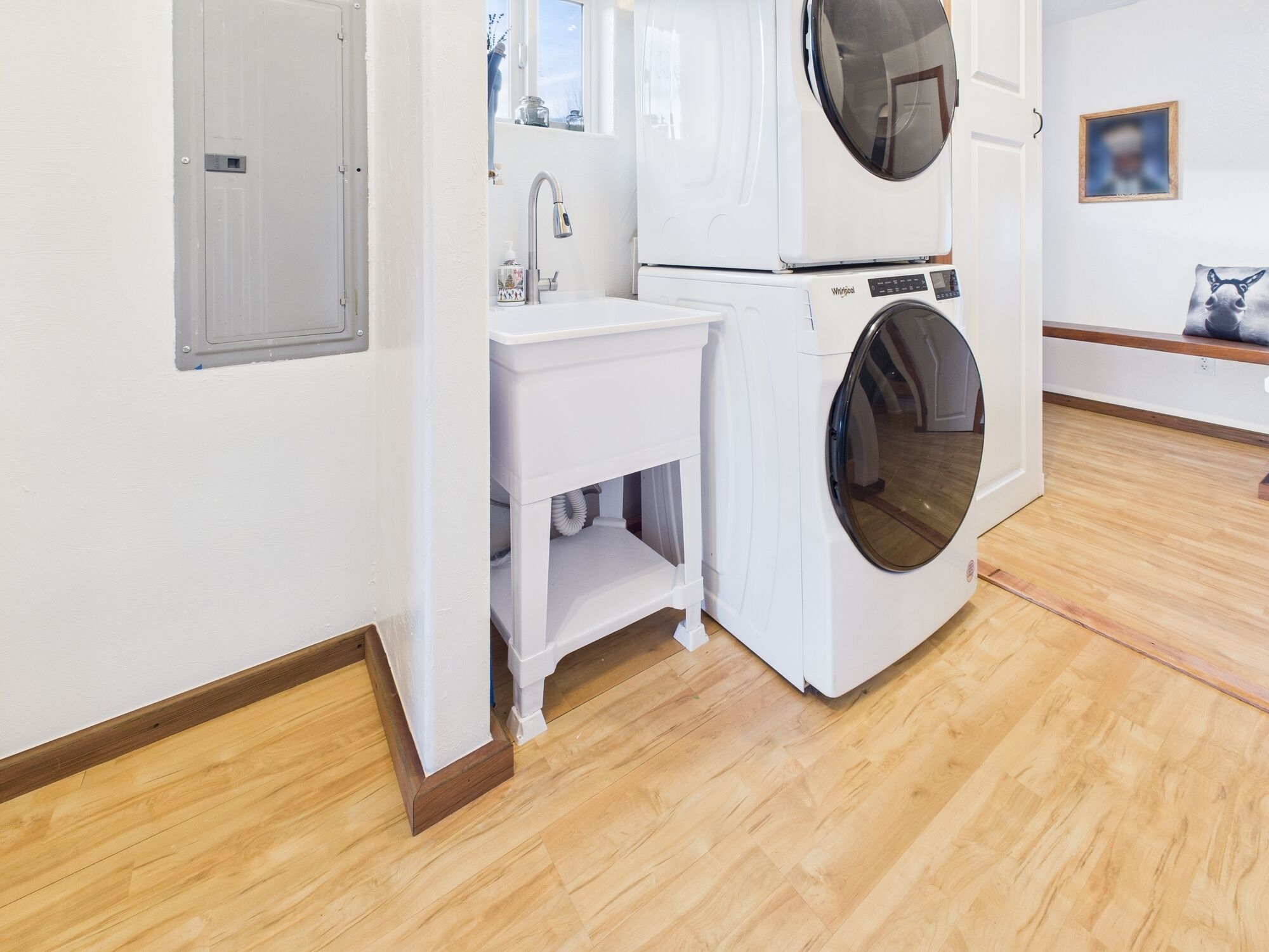 Een wasruimte met een wasmachine, een wasbak en een klein kastje.