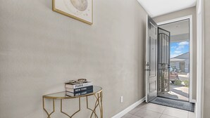 A hallway with a glass door leading outside, a small table with books, and a framed picture on the wall. - Cozy Phoenix Home 4 Bedrooms Family friendly & Fast Wi-Fi (Phoenix)