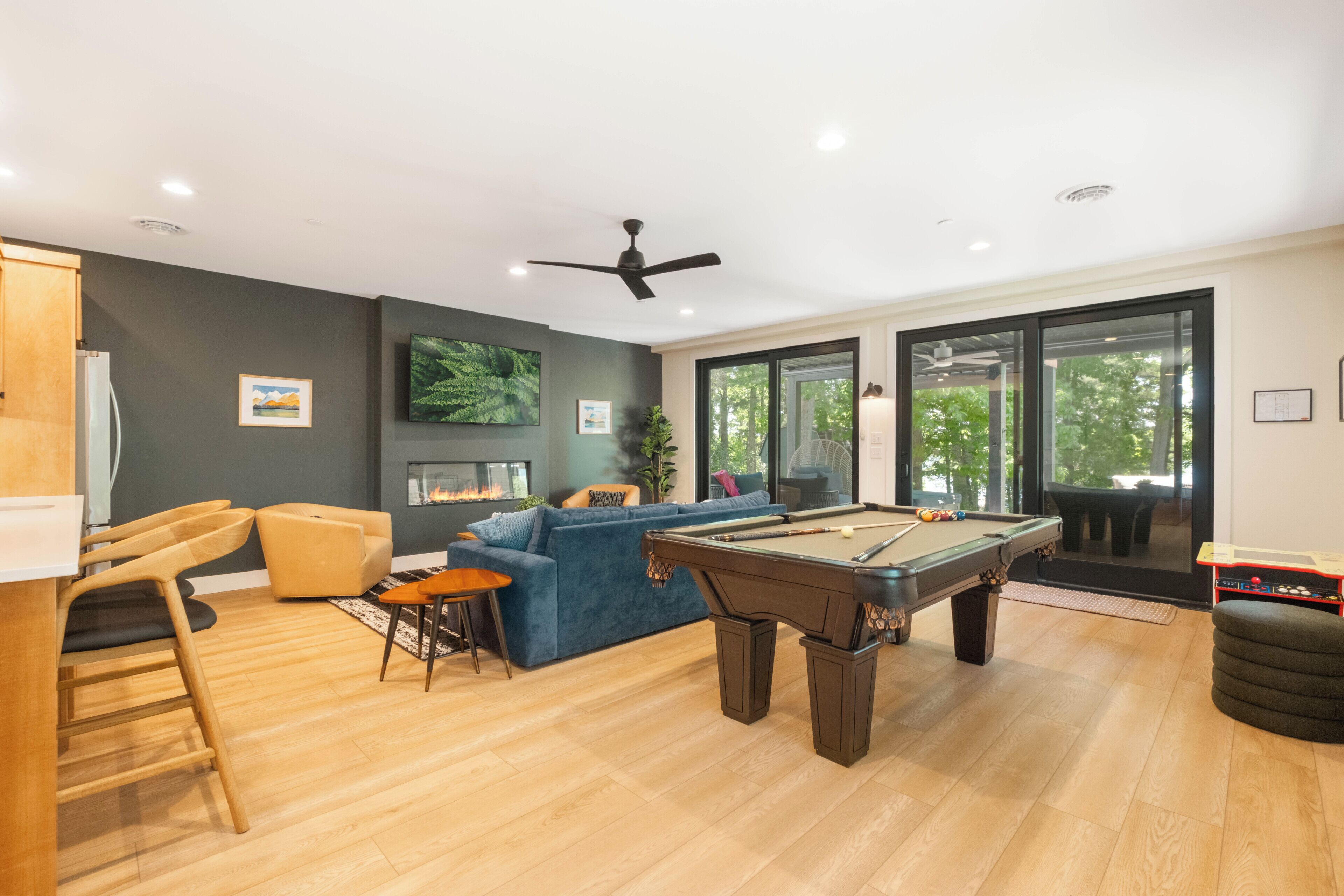 A modern living room with a pool table, a sofa, and a dining area.