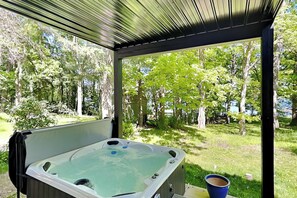 A hot tub under a covered area with a view of a wooded area. - Bear on the Lake (Oakland)