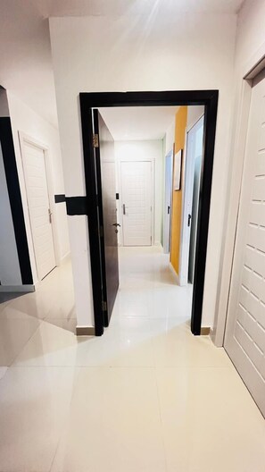 A hallway with white doors and a black-framed door at the end. - Creative Partition Room in Barsha 1 (Dubai)