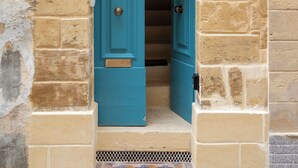 Una puerta azul con un picaporte de metal y un pequeño ventanal encima.