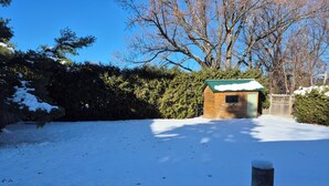 A wooden cabin with a green roof surrounded by snow-covered ground and trees. - Charming 3-bedroom bungalow in peaceful Vaughan with AC and heat. (Vaughan)