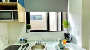 A modern kitchen with a built-in microwave, sink, and wooden cabinets. - Living Alameda (Queretaro)