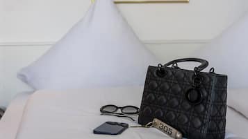 Un lit bien fait, avec un sac à main noir matelassé, une paire de lunettes et un porte-clés orné du numéro 305.