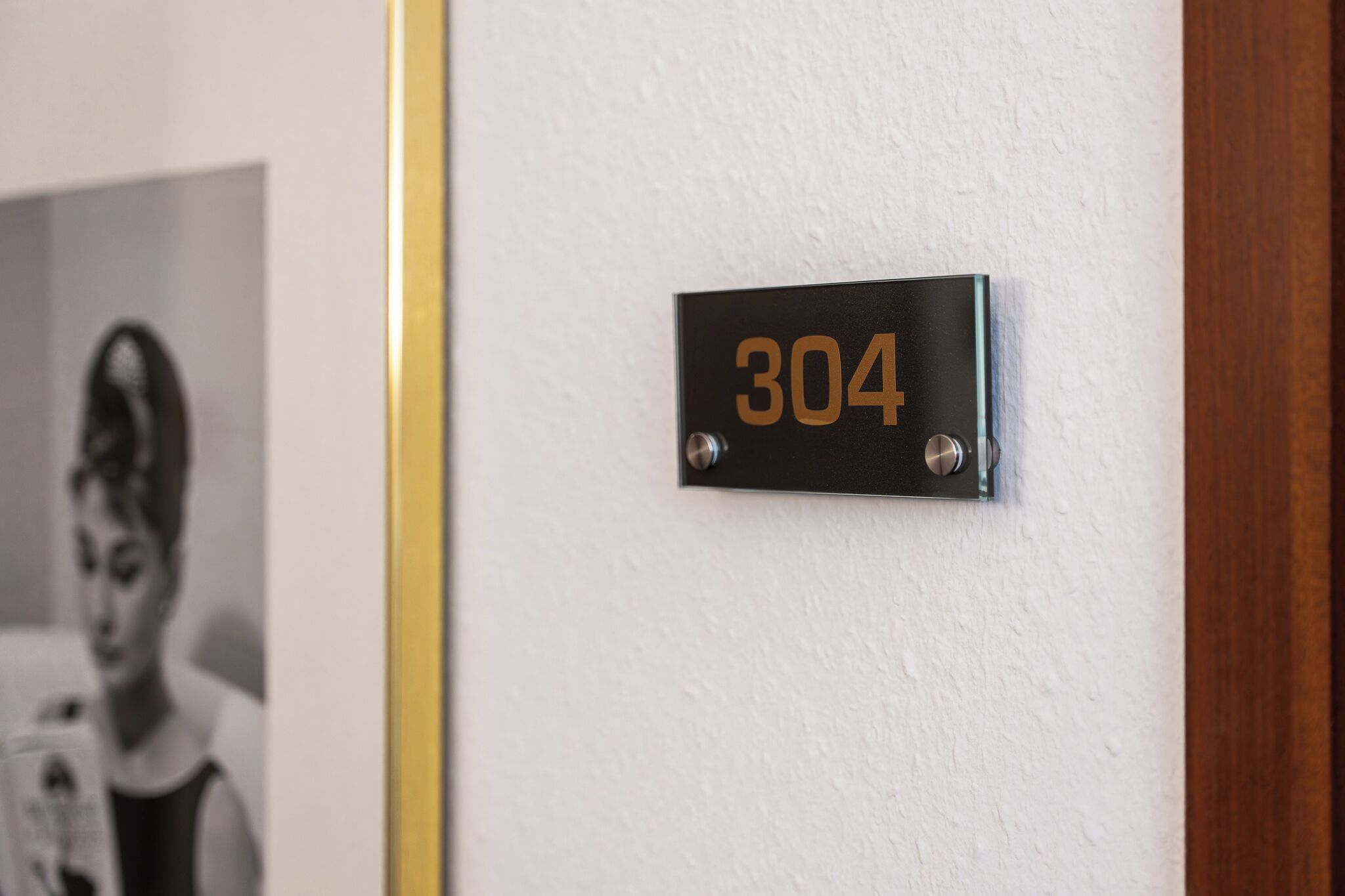 Musta metallilaatta, jossa on numero ’304’, on kiinnitetty valkoiseen seinään.