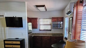A kitchen with dark wooden cabinets, a built-in microwave, and a window with blinds. - 110 Signature Single Room in waterfront hotel in Singer Island, FL (Riviera Beach)