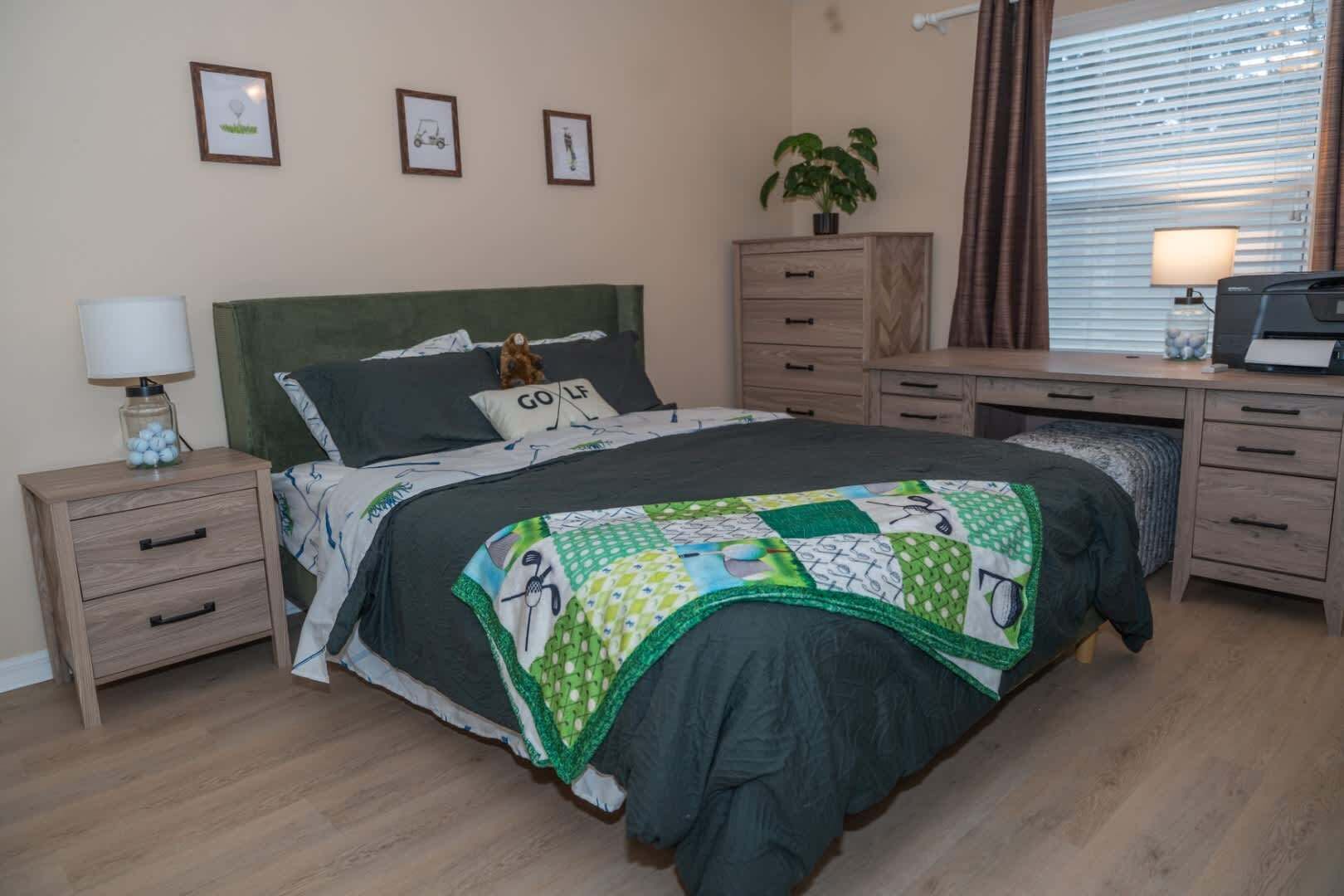 A neatly arranged bedroom with a bed, bedside tables, a desk, and a window with blinds.